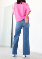 Person wearing a pink sweater and blue jeans against a white background