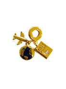 A gold-toned travel-themed charm keychain featuring a miniature airplane, a globe charm, a padlock with a clear rhinestone, and a small luggage tag, displayed on a light textured surface.