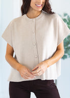 Woman wearing a beige button-up top against a light blue background
