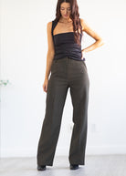 Woman wearing a black top and dark green pants on a white background