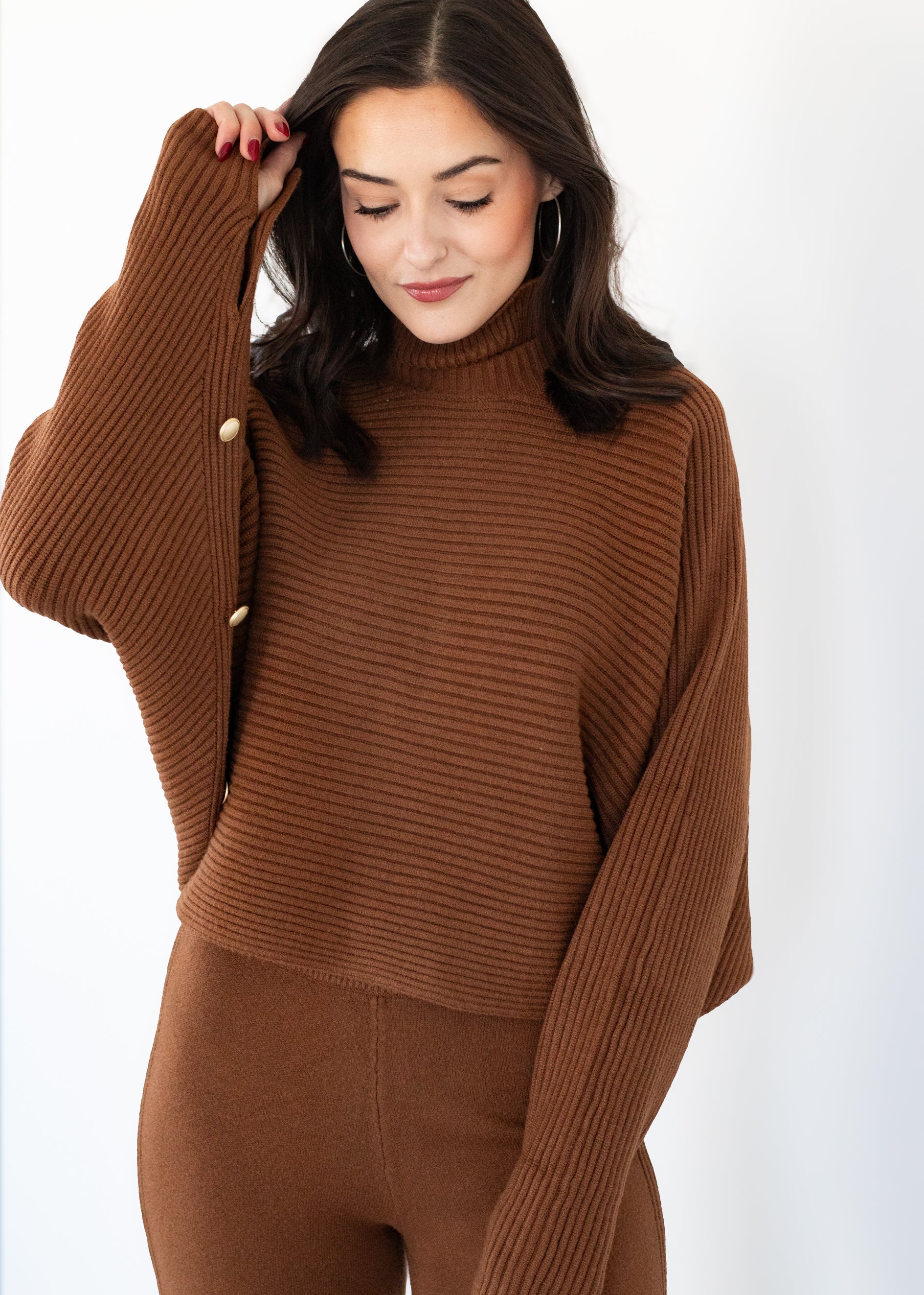 Woman wearing a brown ribbed sweater and pants on a white background