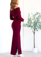 Woman wearing a burgundy off-shoulder dress with a plant in the background