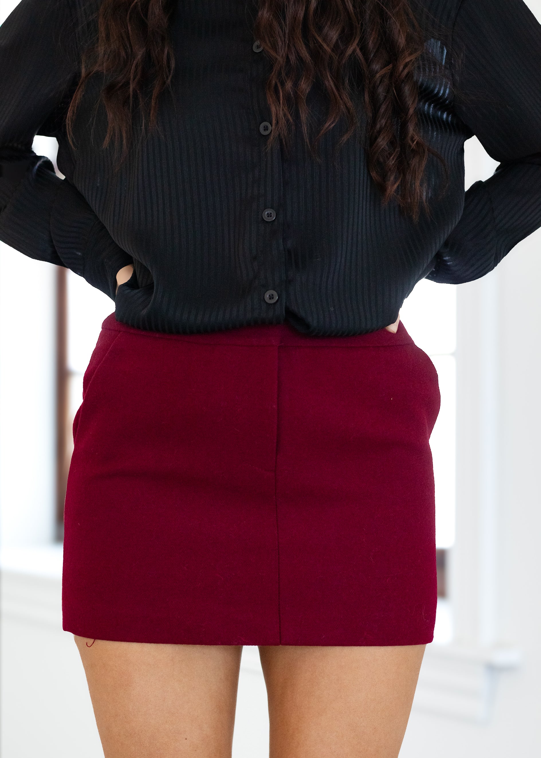 Person wearing a black shirt and red skirt with a blurred background
