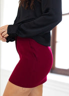 Person wearing a black sweater and red skirt with a blurred background
