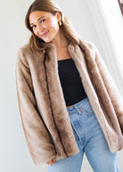 Woman wearing a beige fur coat with a plain background