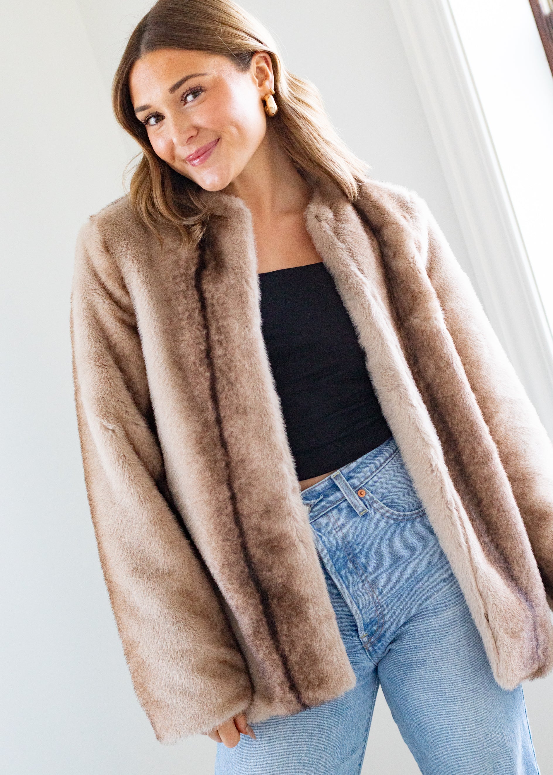 Woman wearing a beige fur coat with a plain background