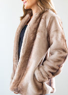 Beige fur coat worn by a person on a white background
