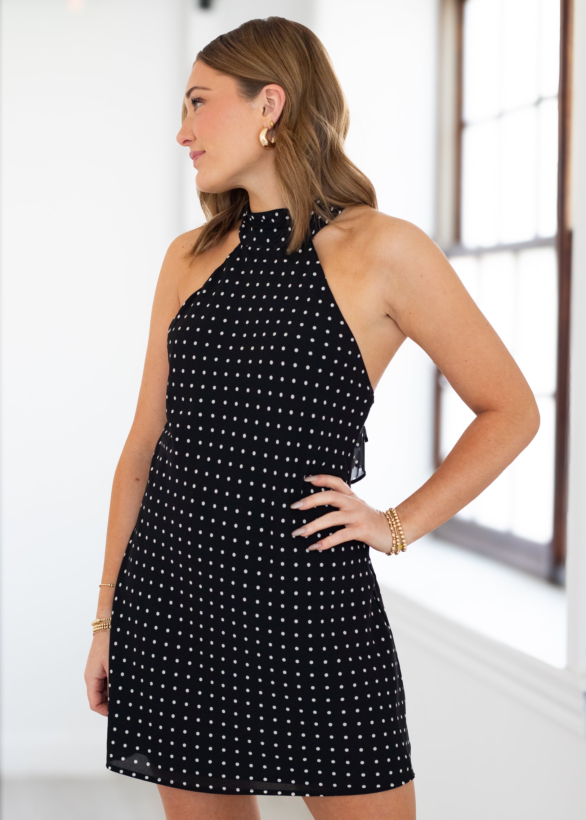 Woman wearing a black dress with white polka dots indoors.
