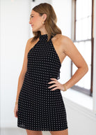Woman wearing a black dress with white polka dots indoors.