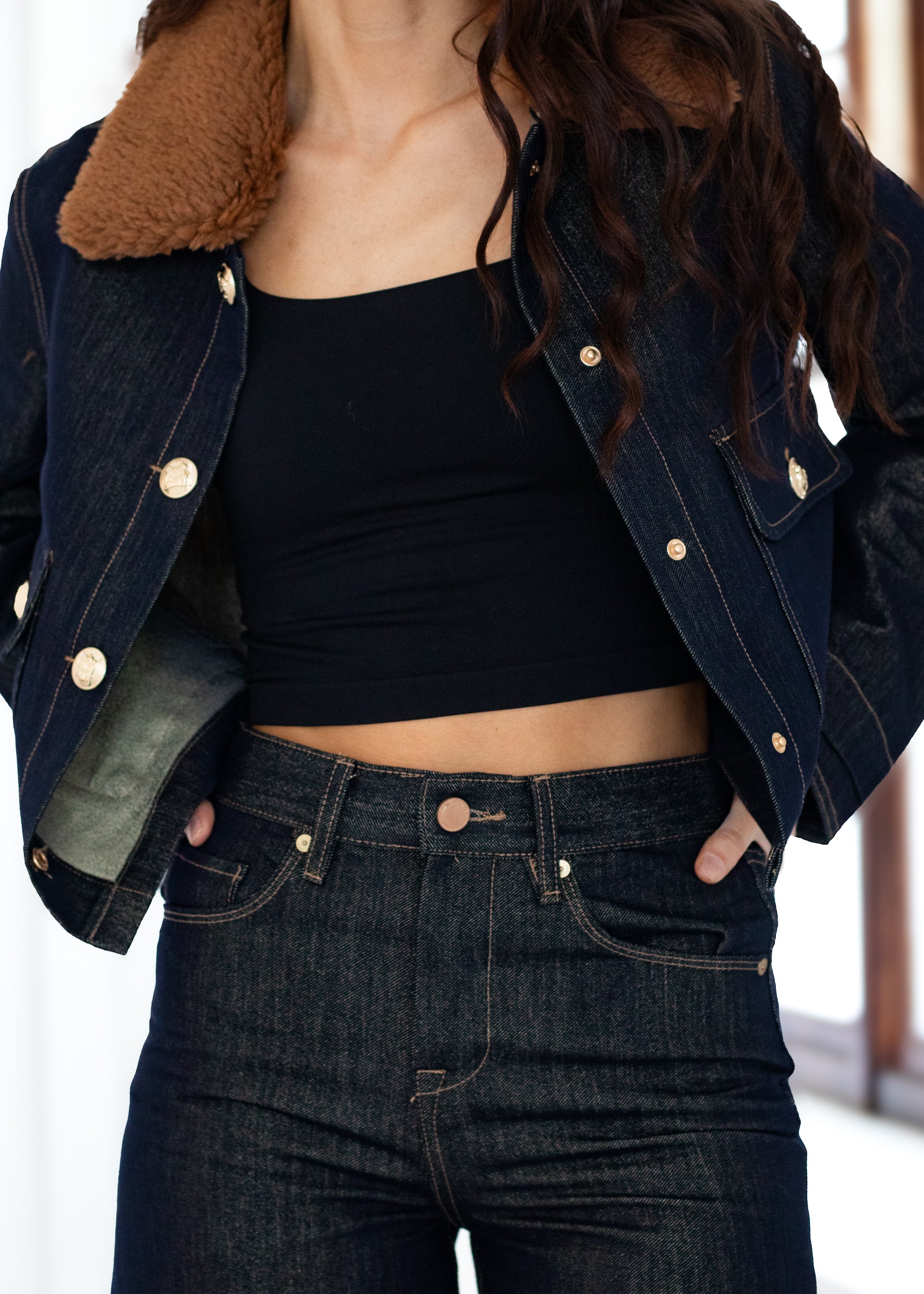 Person wearing a dark denim jacket and jeans with a blurred background