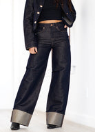 Person wearing dark blue wide-leg jeans with a white background