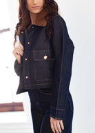 Person wearing a dark denim jacket with a fur collar against a white background