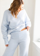 Woman wearing a light blue sweater and pants in a minimalistic setting