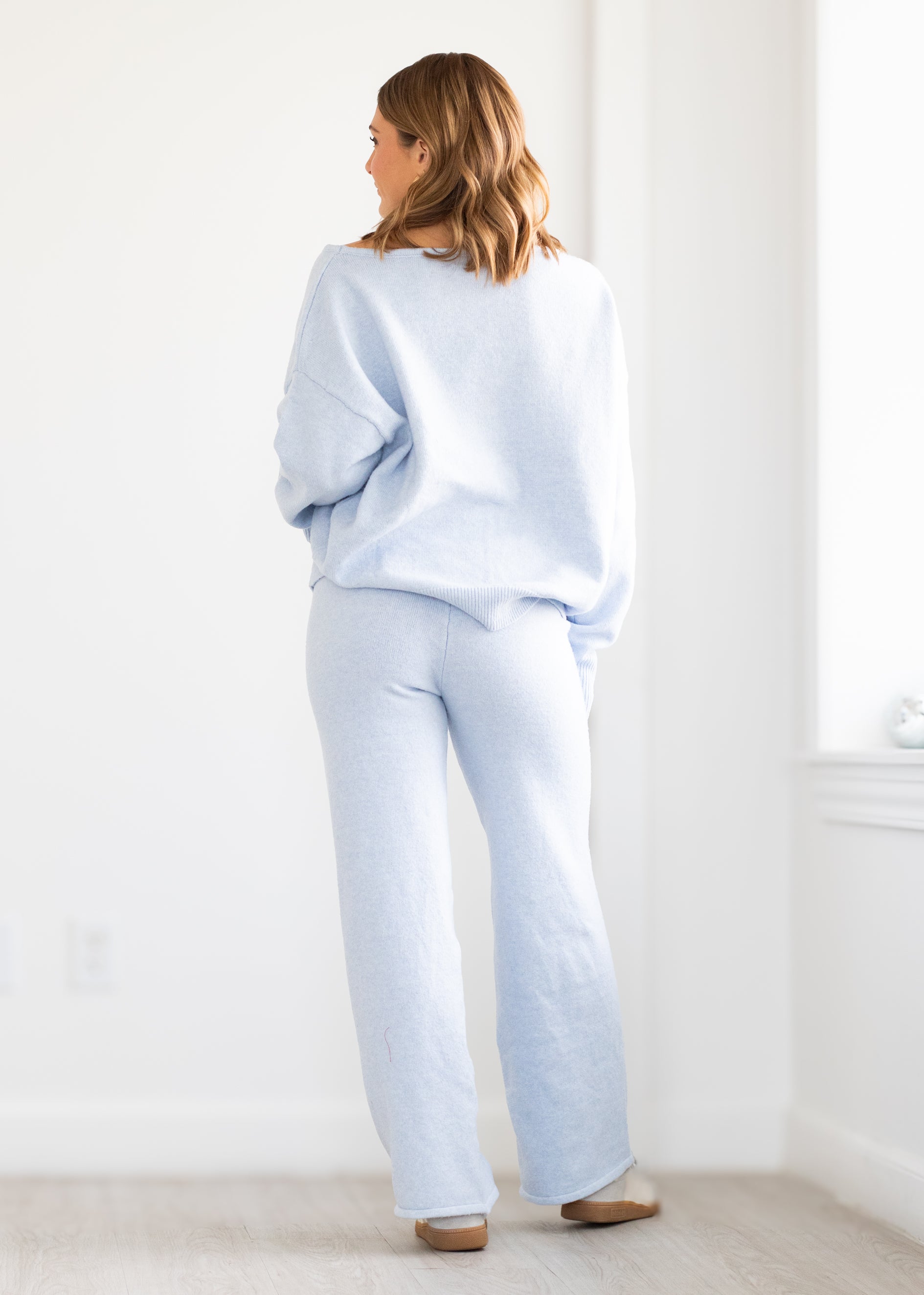 Woman wearing a light blue outfit standing in a minimalistic room.