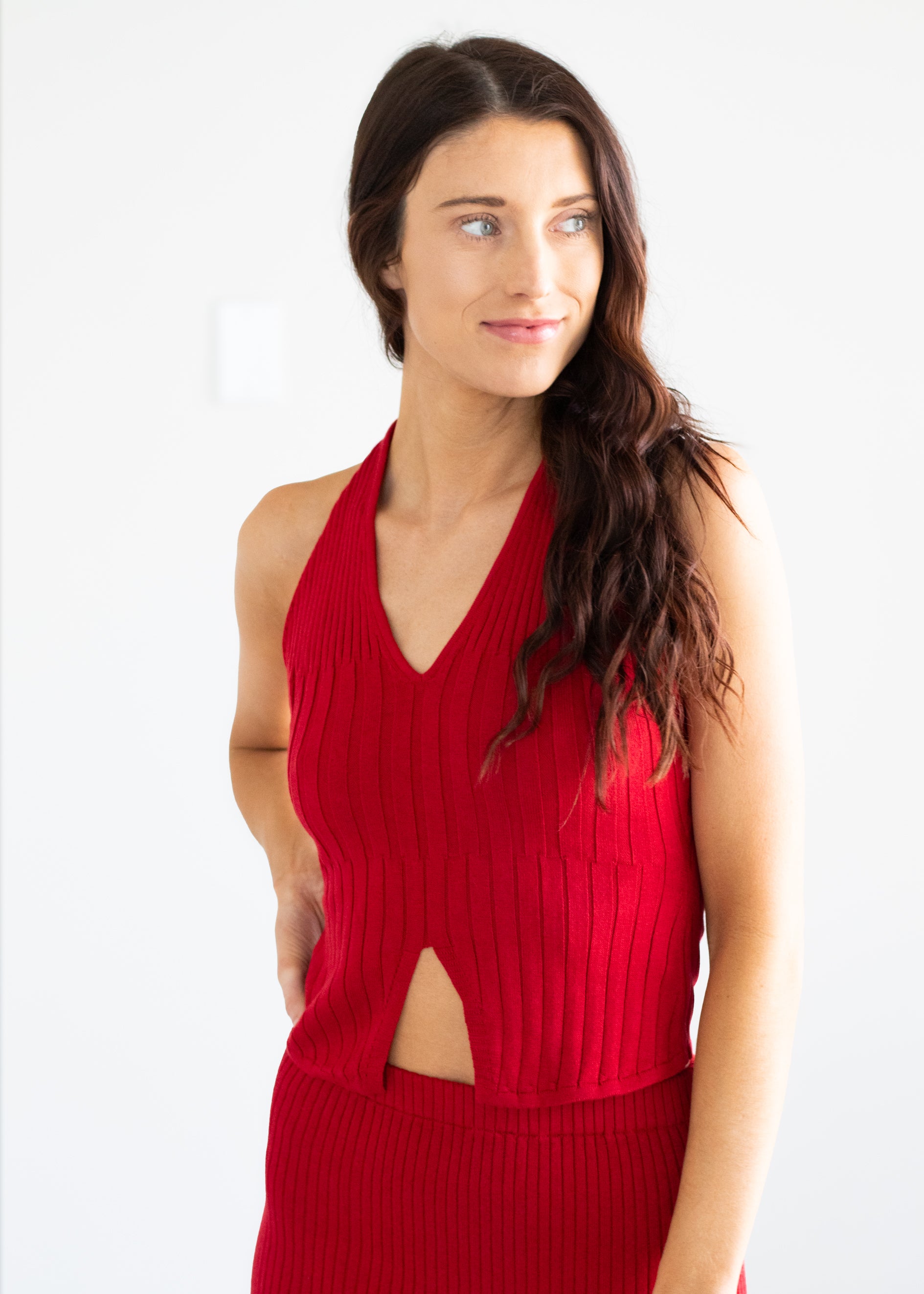 Woman wearing a red sleeveless top with a cutout design on a white background