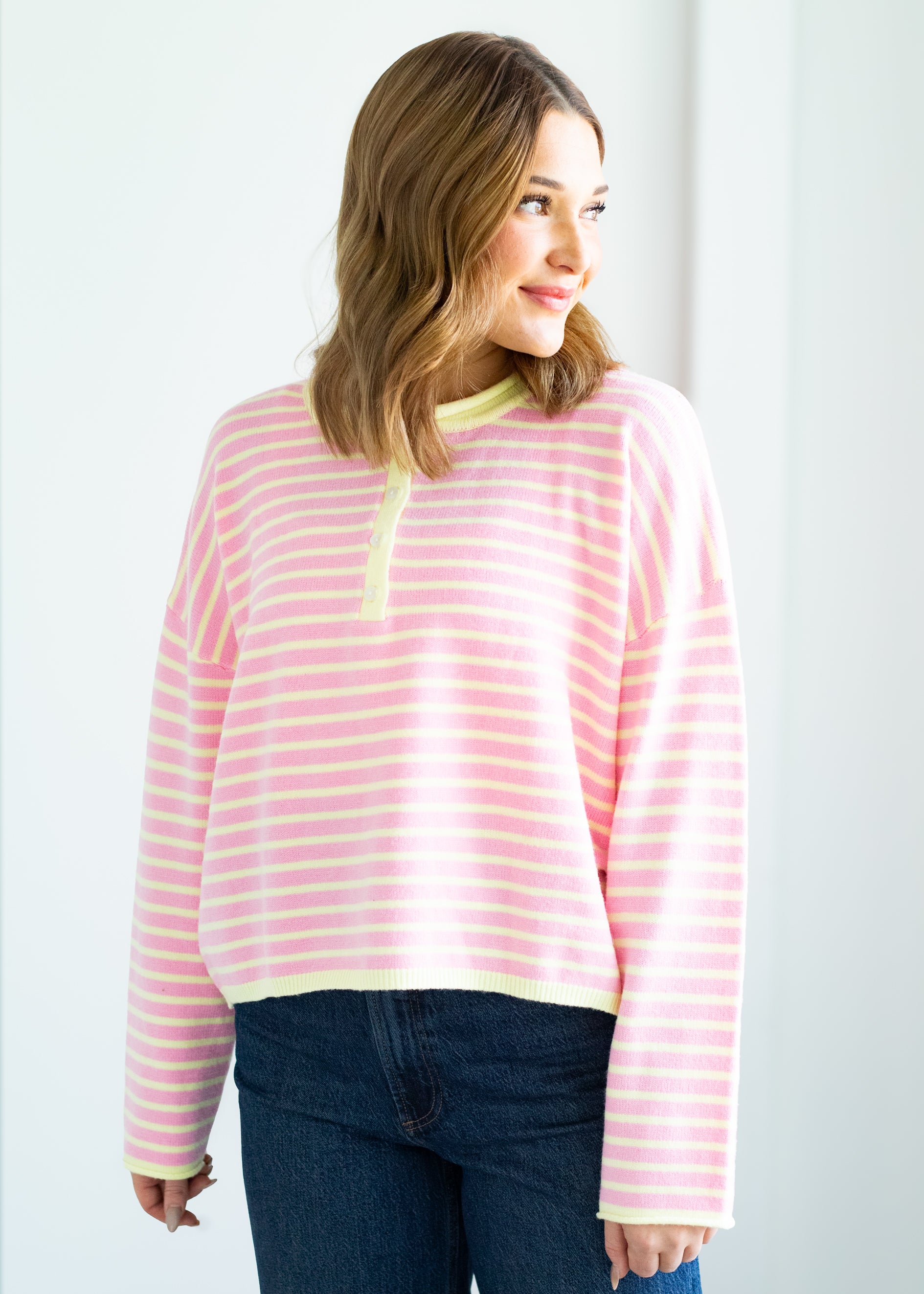 Woman wearing a pink and yellow striped sweater against a plain background