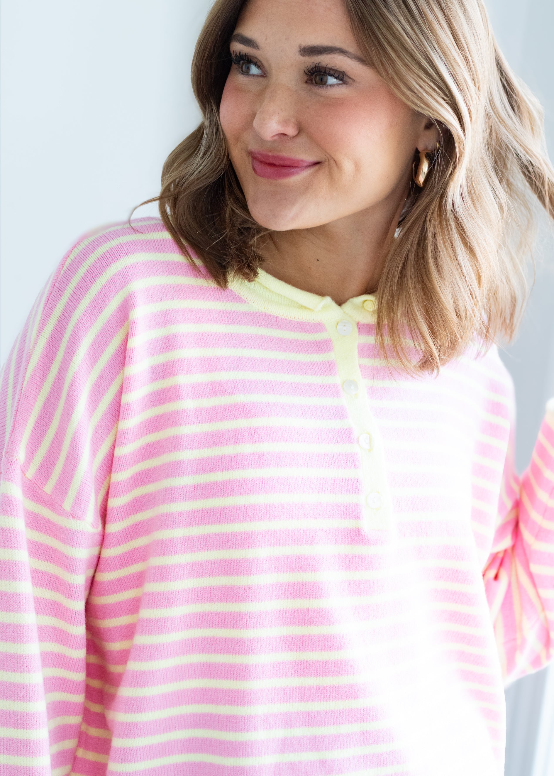 Woman wearing a pink and yellow striped sweater against a light gray background