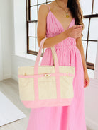 Woman in a pink dress holding a pink and beige tote bag indoors.