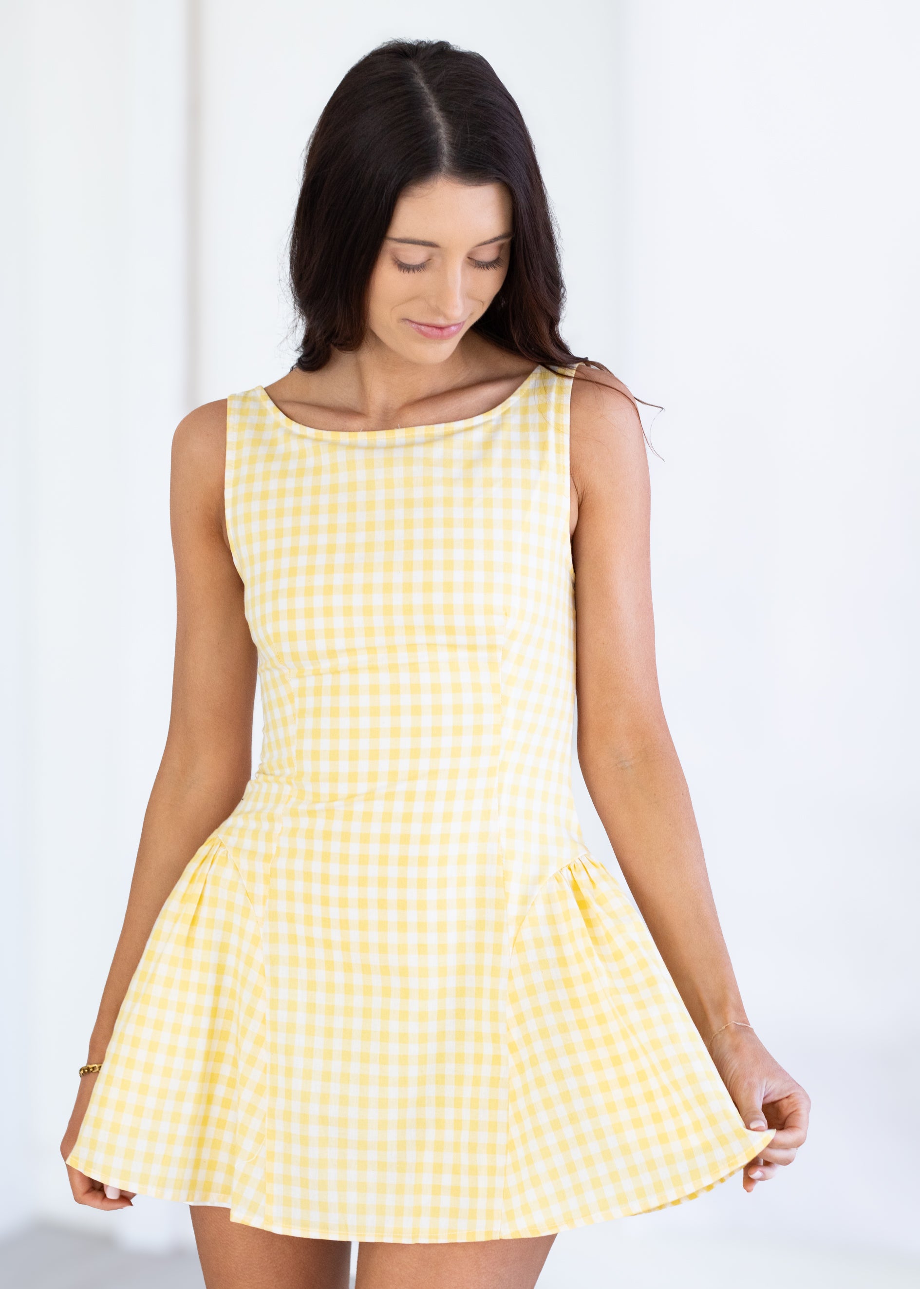 Woman wearing a yellow checkered dress against a white background
