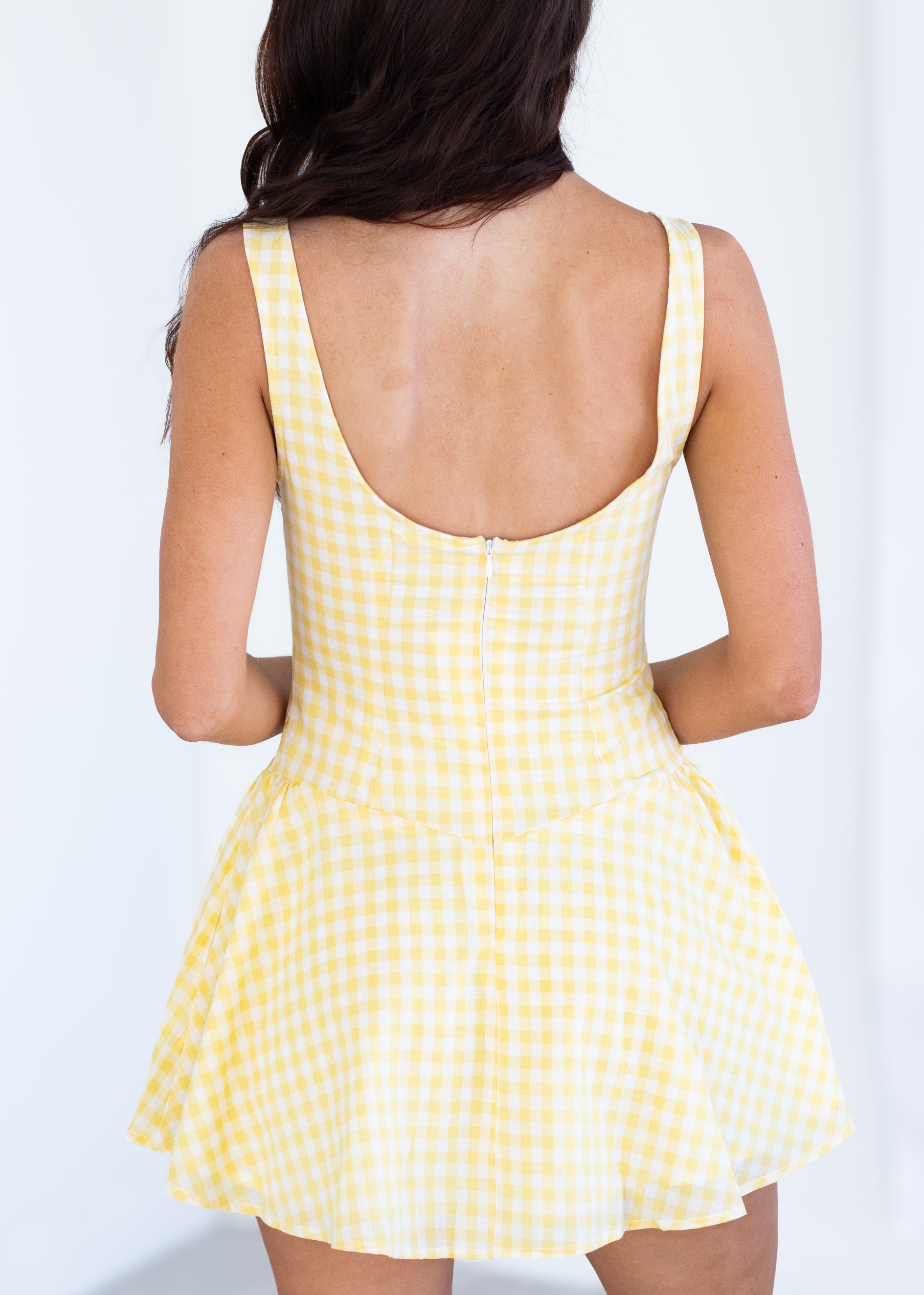 Yellow checkered dress worn by a person on a white background