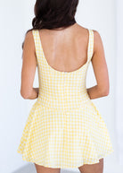 Yellow checkered dress worn by a person on a white background