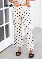 Person wearing polka dot pants in a room with a white door.