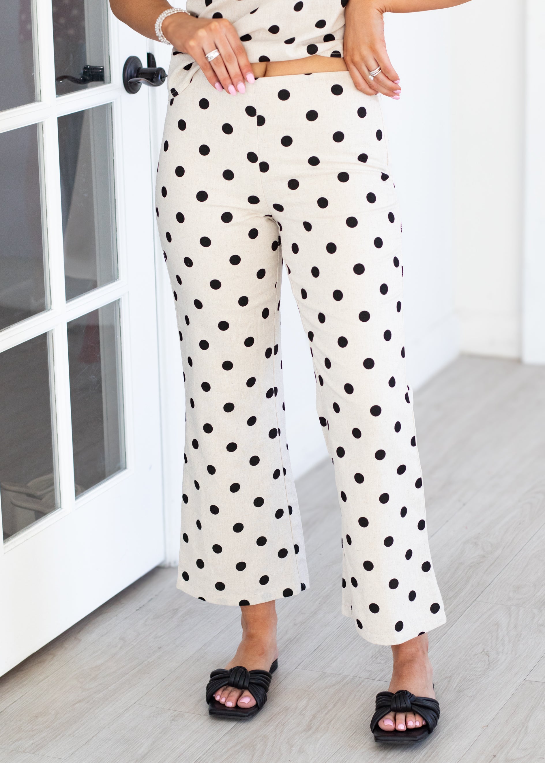 Person wearing polka dot pants in a room with a white door.