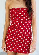 Red strapless dress with white polka dots on a plain background