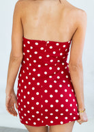 Red strapless dress with white polka dots on a plain background