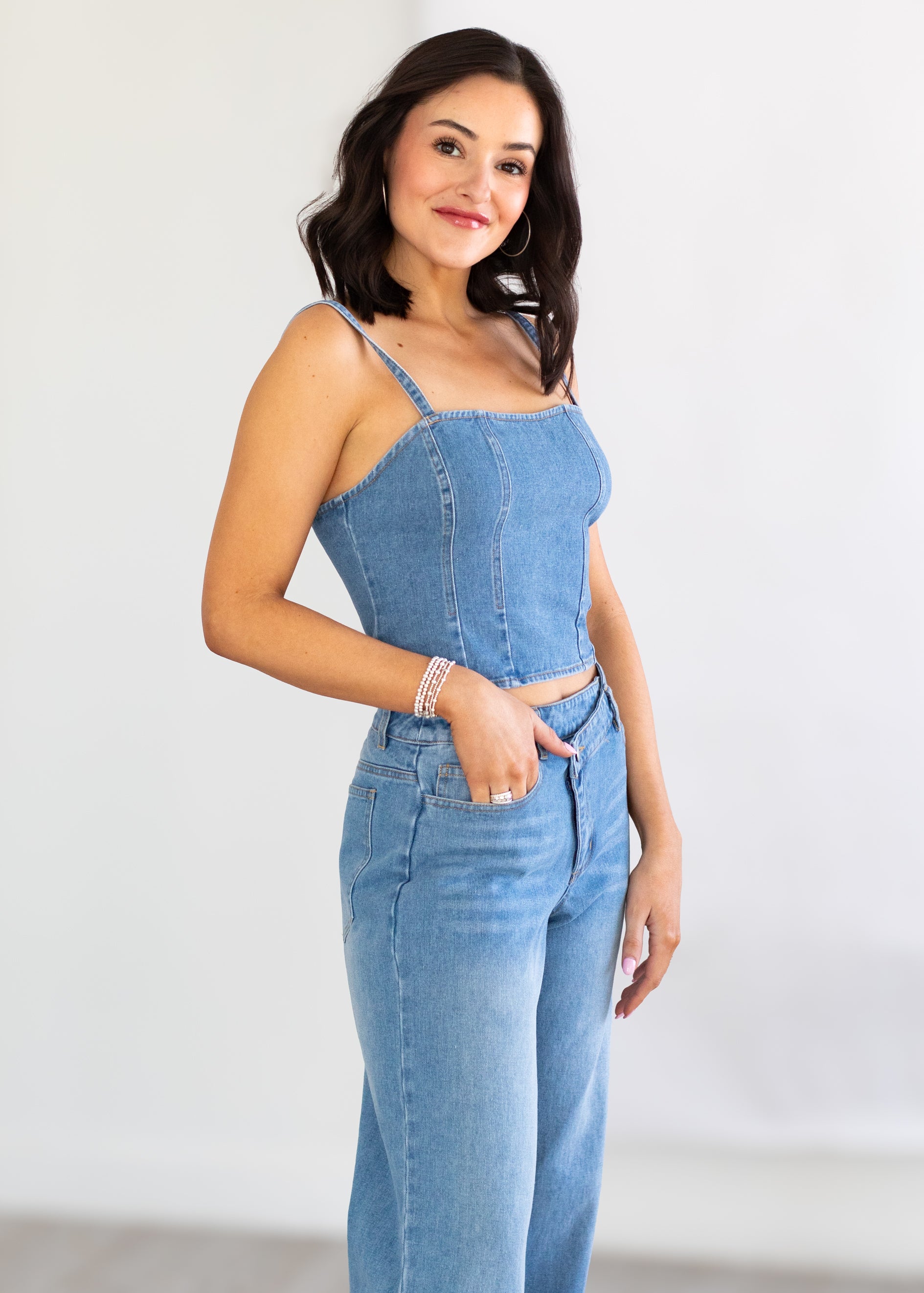 Woman wearing a blue denim jumpsuit against a white background