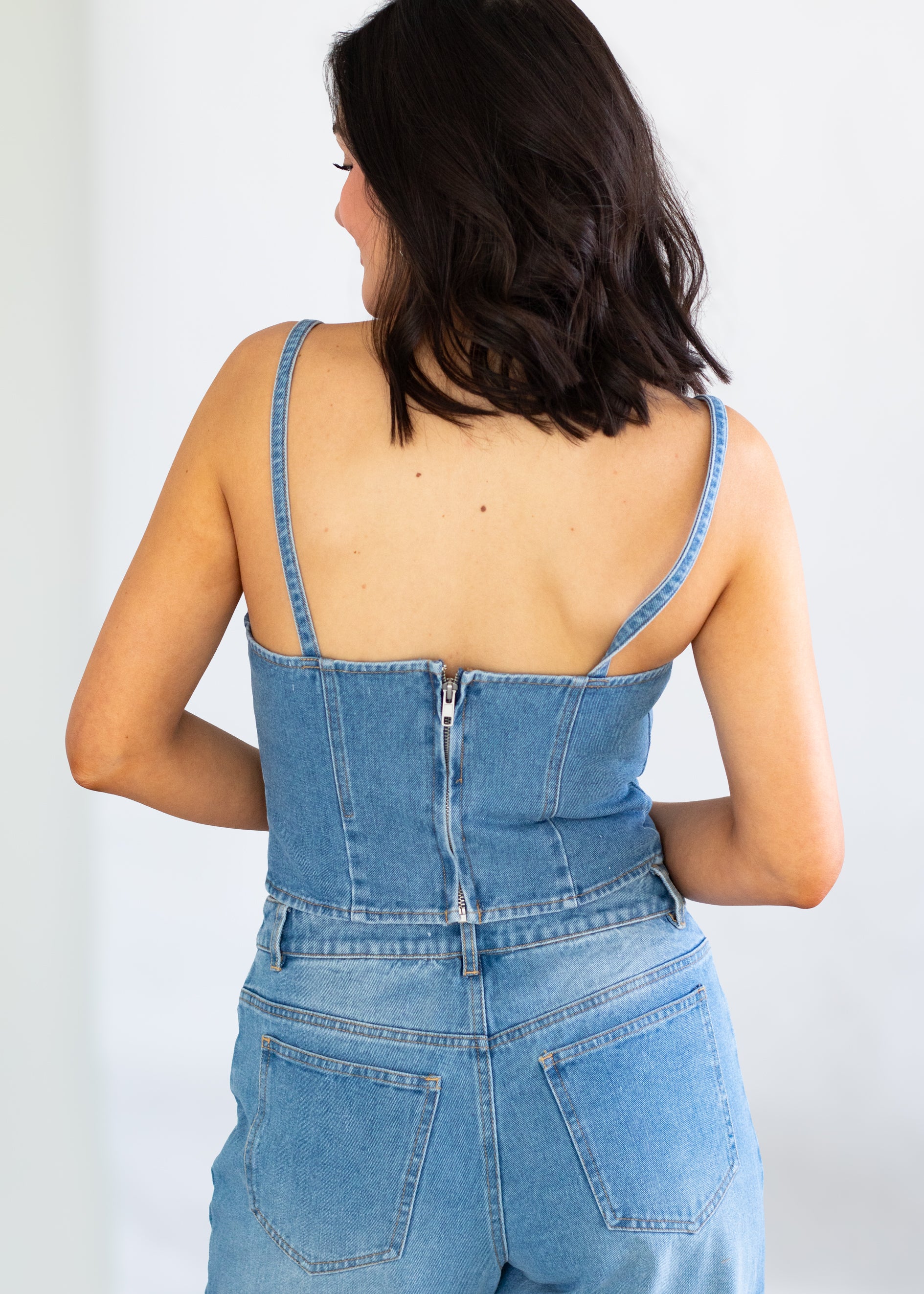 Woman wearing a blue denim set against a white background