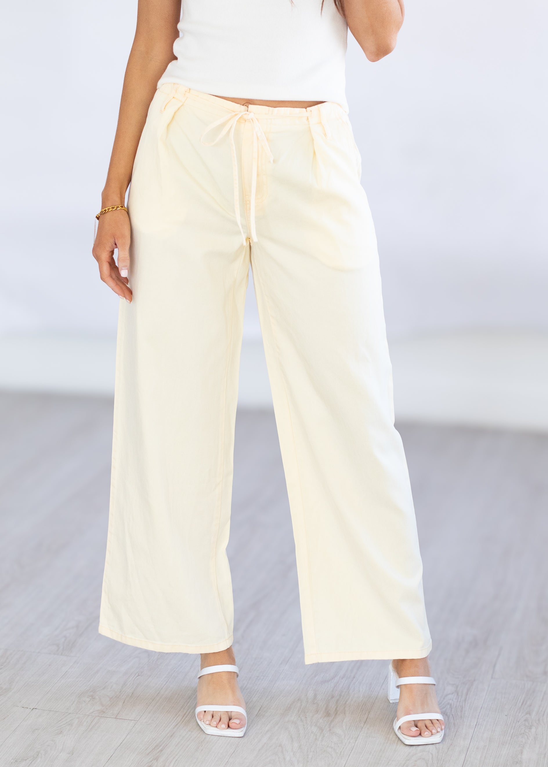 Person wearing light-colored yellow wide-leg pants on a plain background