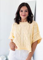 Woman wearing a light yellow knitted sweater against a white background