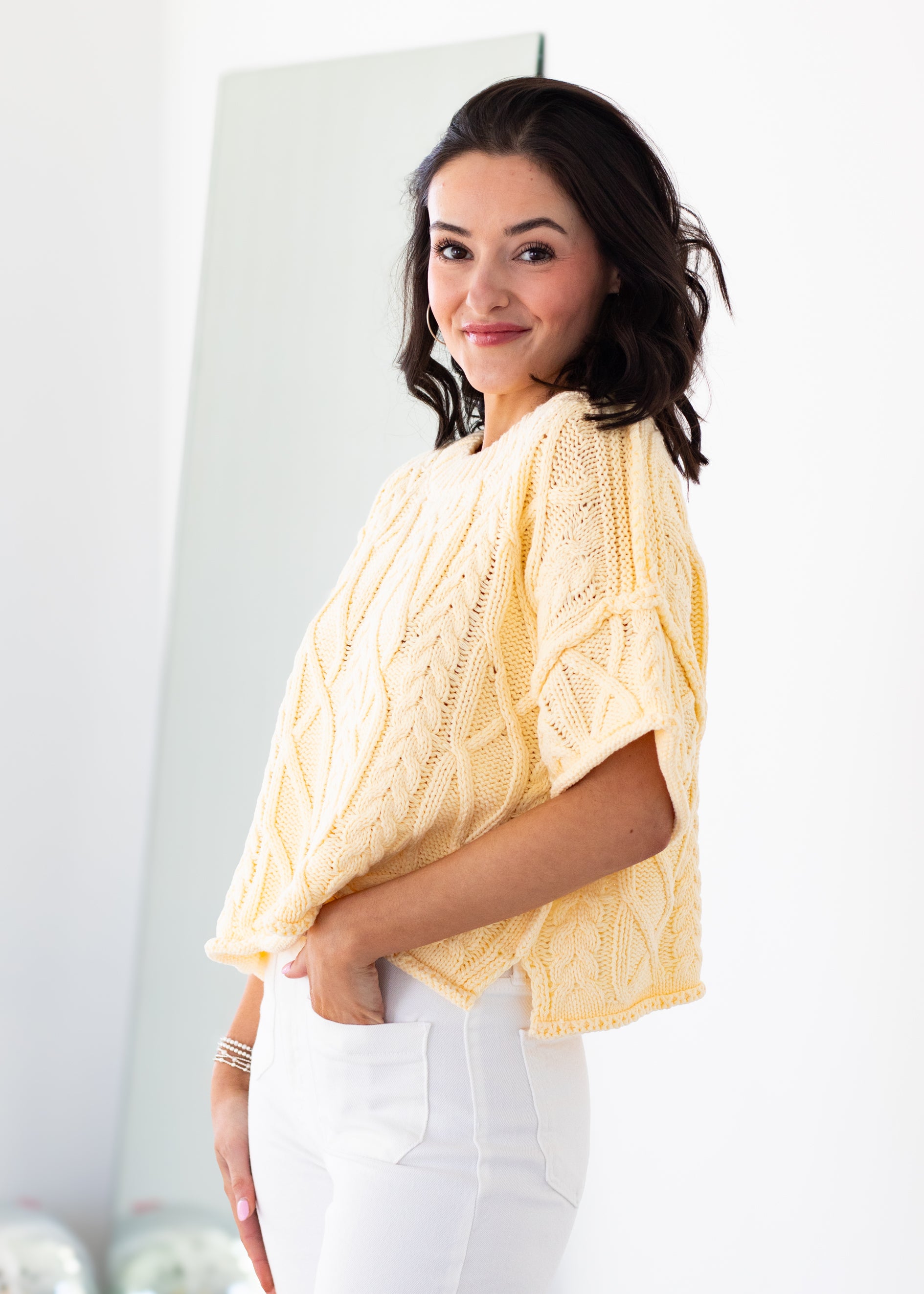 Woman wearing a yellow knitted sweater against a white background