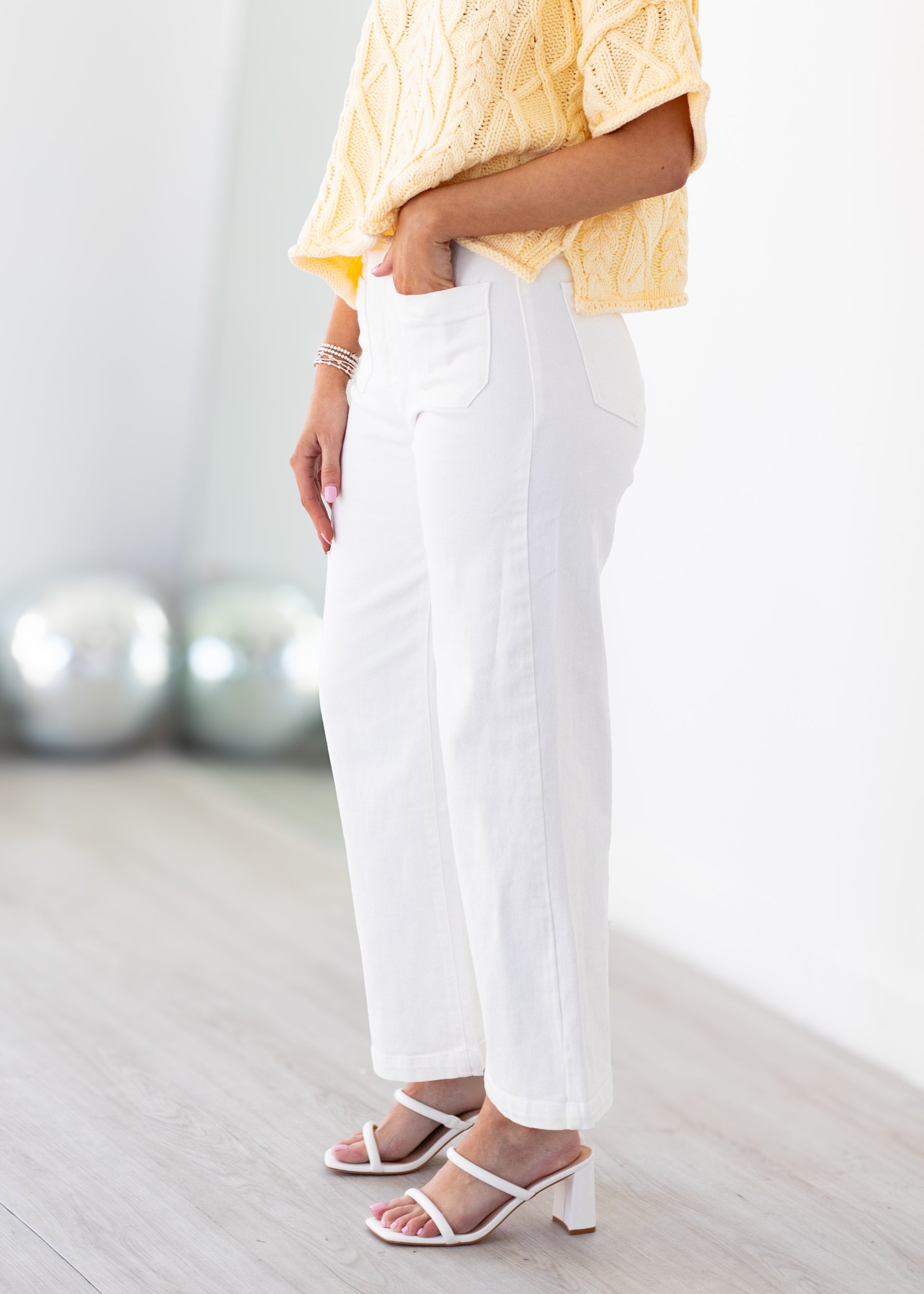 Person wearing a yellow top and white pants in a minimal indoor setting