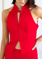 Red sleeveless top with a tie detail worn by a person on a white background
