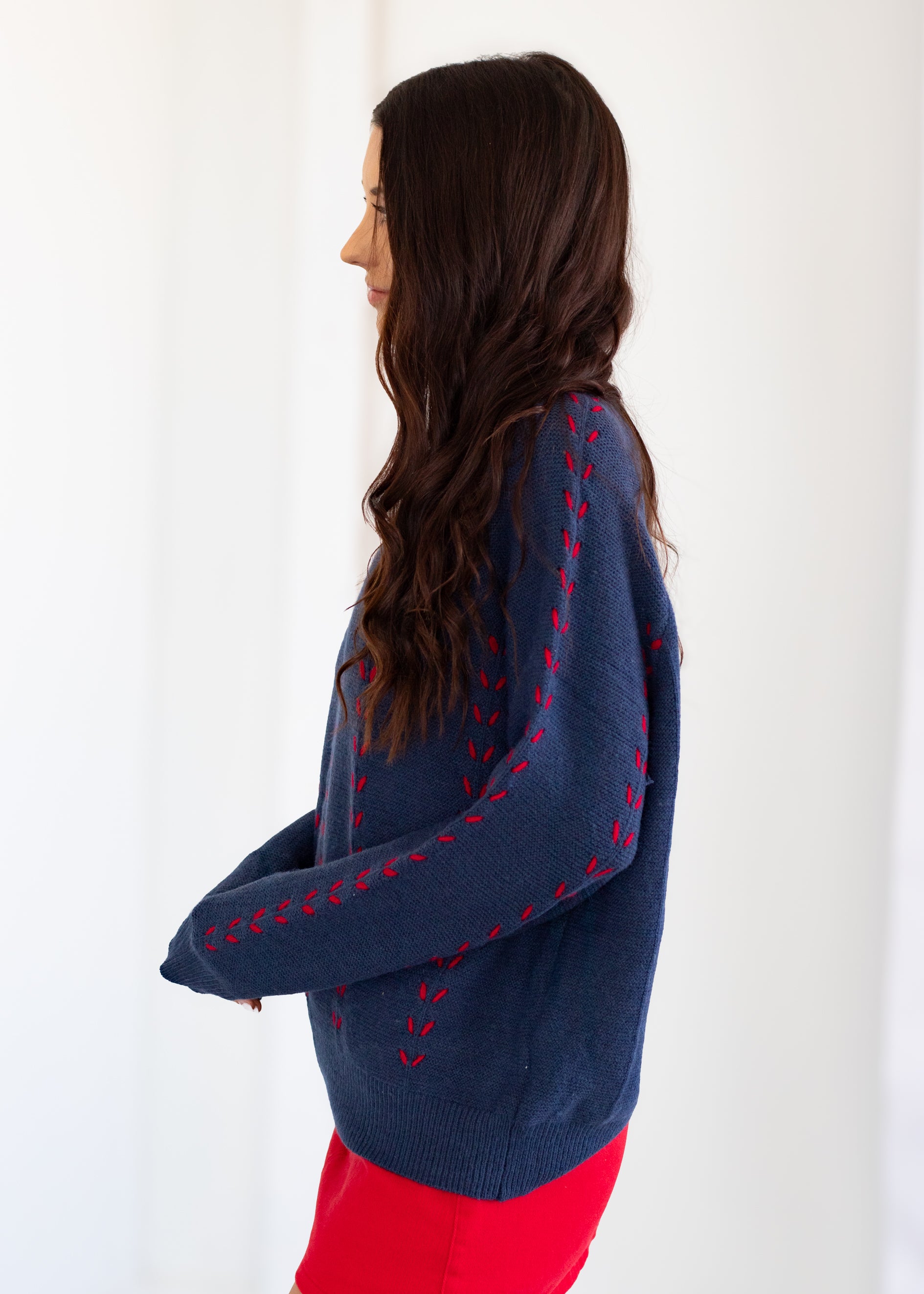 Woman wearing a blue sweater with red patterns against a white background