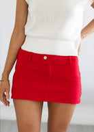 Red skirt worn with a white top on a plain background