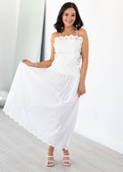 Woman wearing a white matching top and skirt set with lace details in a minimal indoor setting