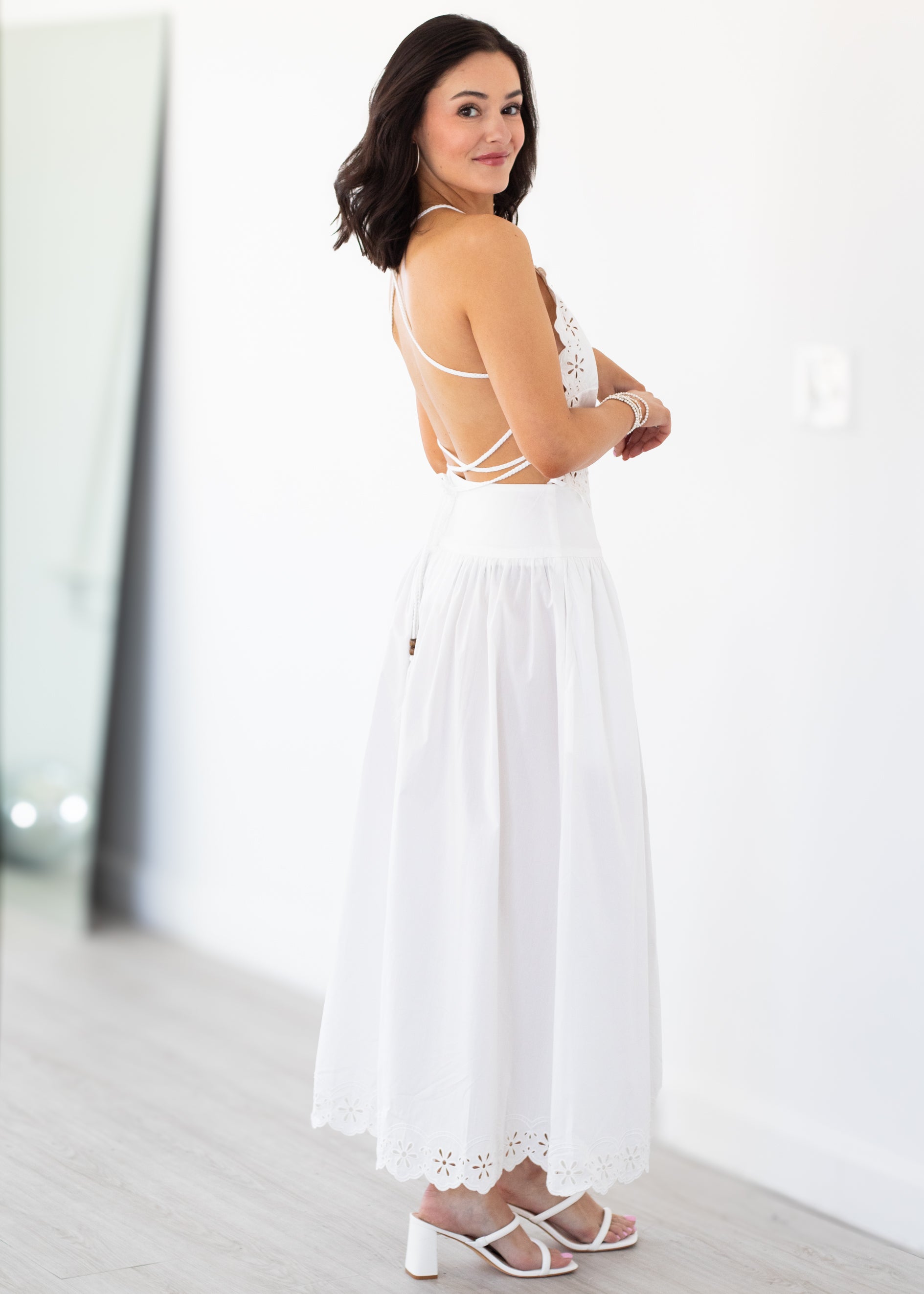 Woman wearing a white set with cut-out details on a white background