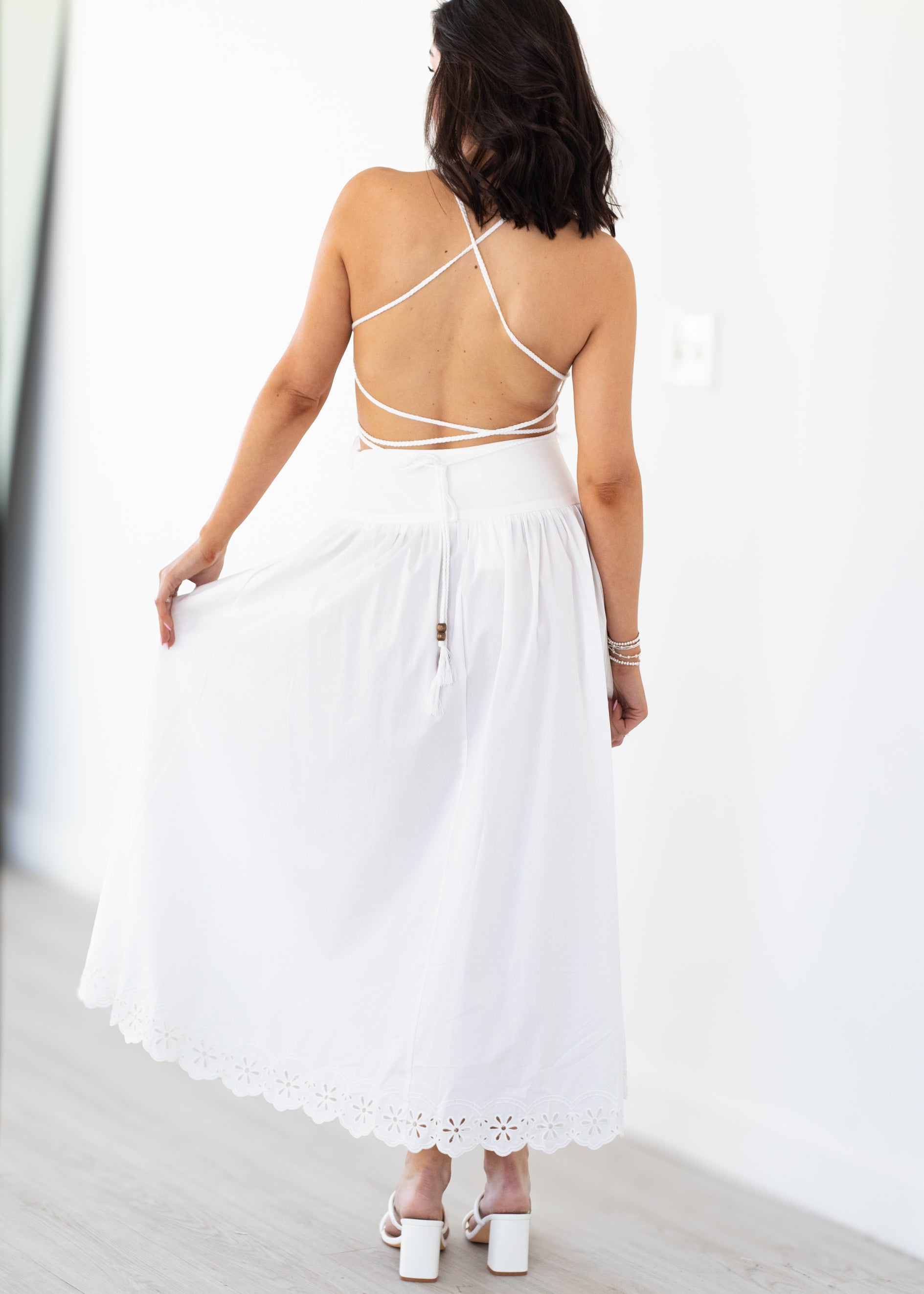 Woman wearing a white set with thin straps against a white background