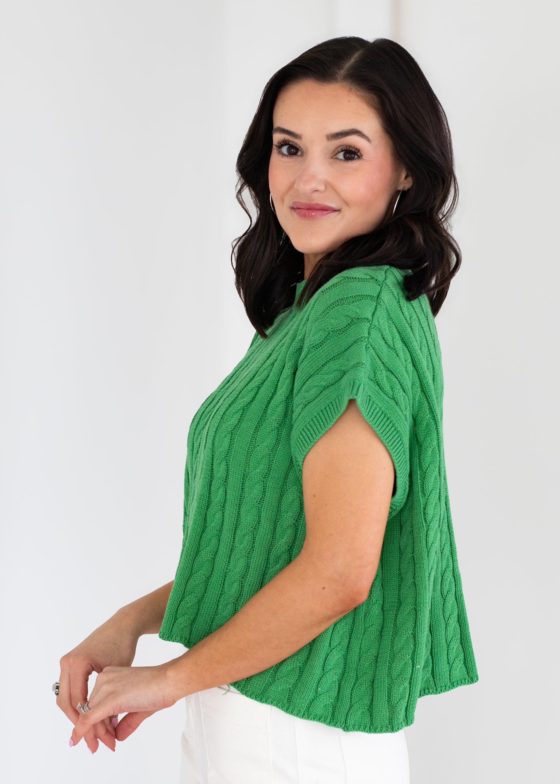 Woman wearing a green knitted vest against a white background