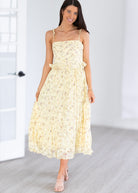 Woman wearing a yellow floral dress in a minimal indoor setting