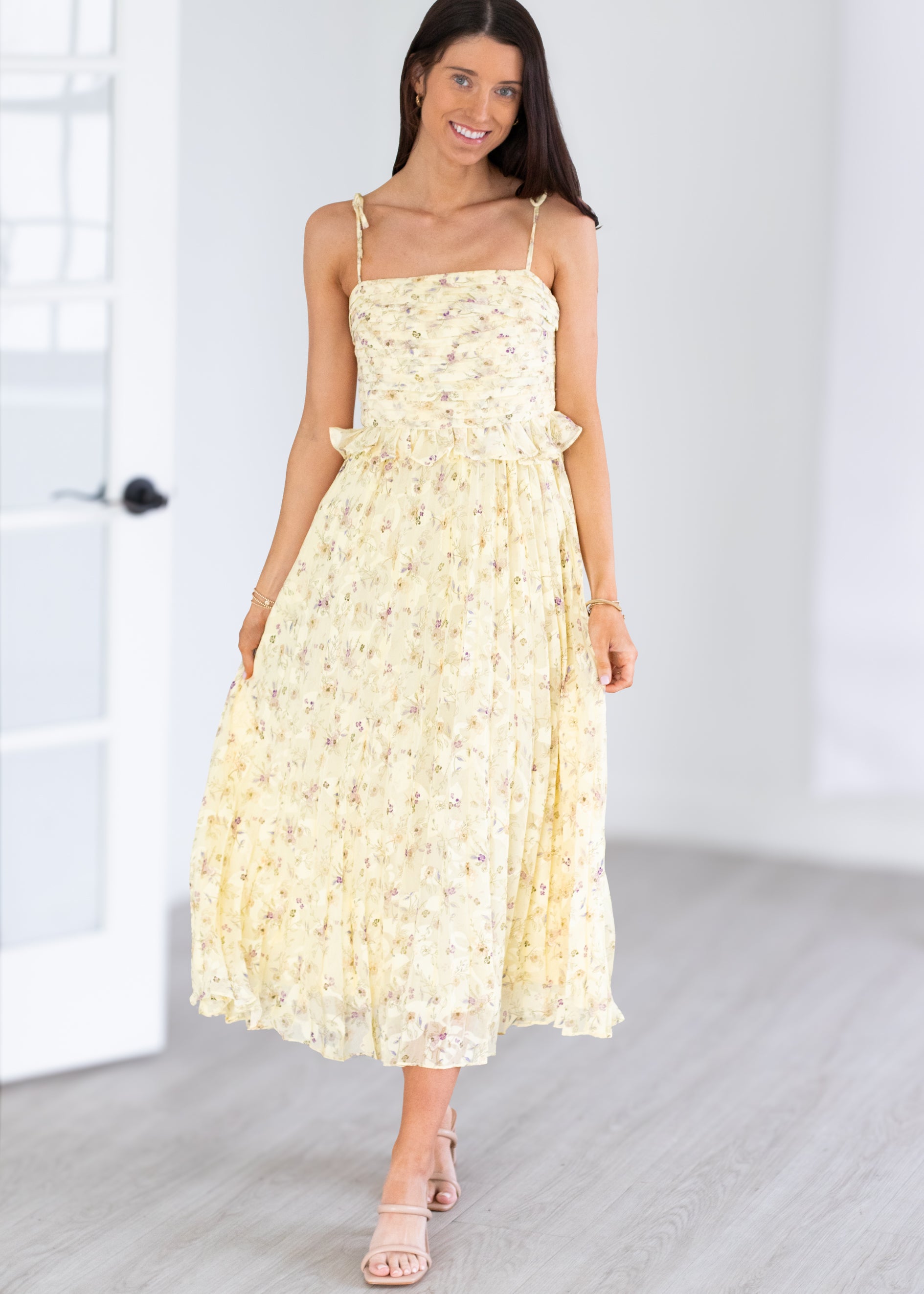 Woman wearing a yellow floral dress in a minimal indoor setting