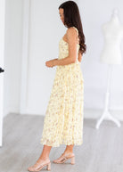 Woman wearing a light yellow floral dress in a minimal indoor setting