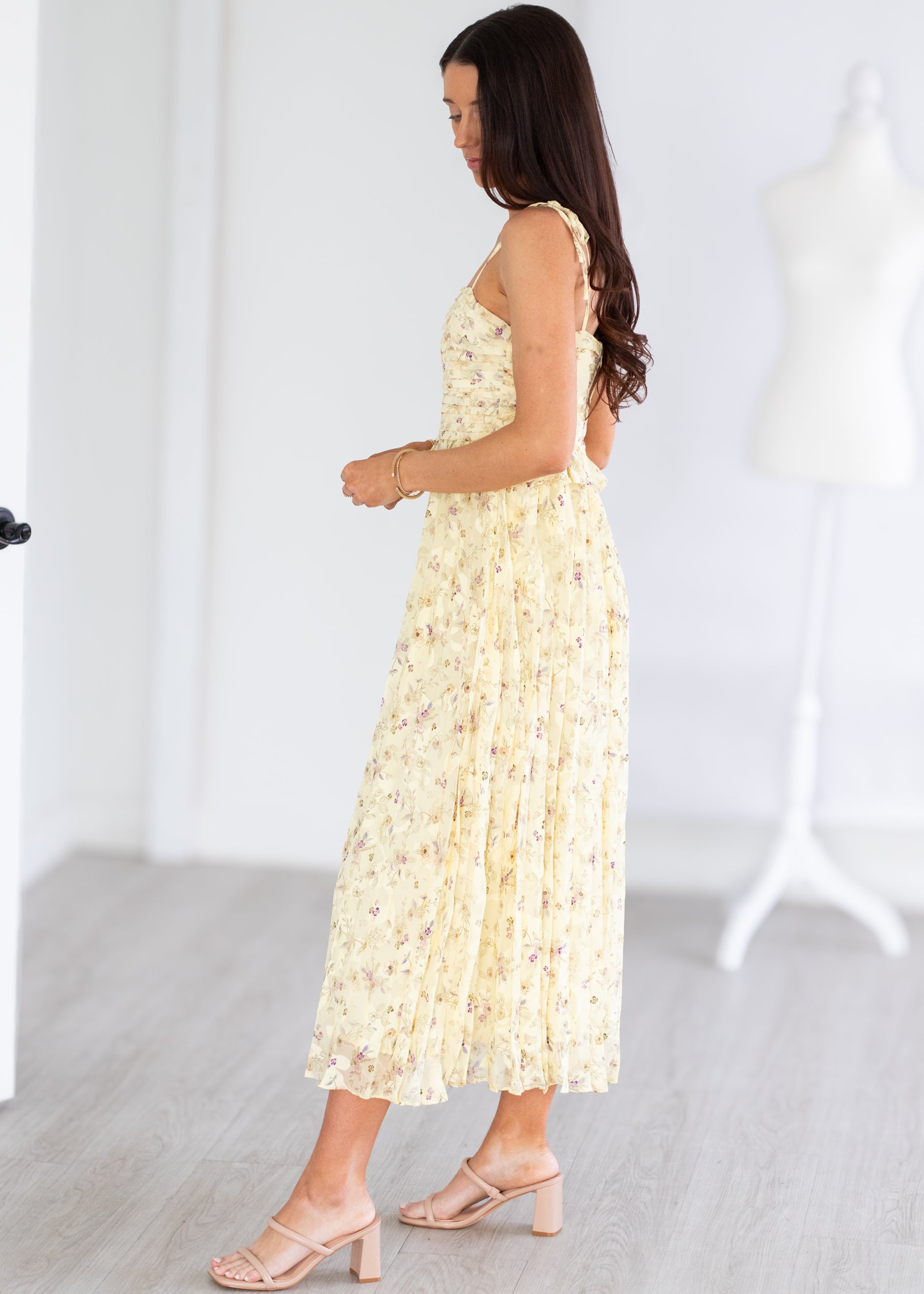 Woman wearing a light yellow floral dress in a minimal indoor setting