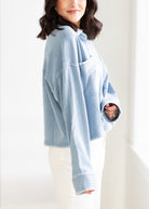 Woman wearing a light blue oversized sweater against a white background