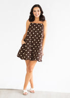 Woman wearing a brown dress with white polka dots on a white background