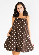 Woman wearing a brown dress with white polka dots on a white background