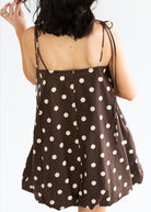 Brown polka dot dress worn by a person on a white background